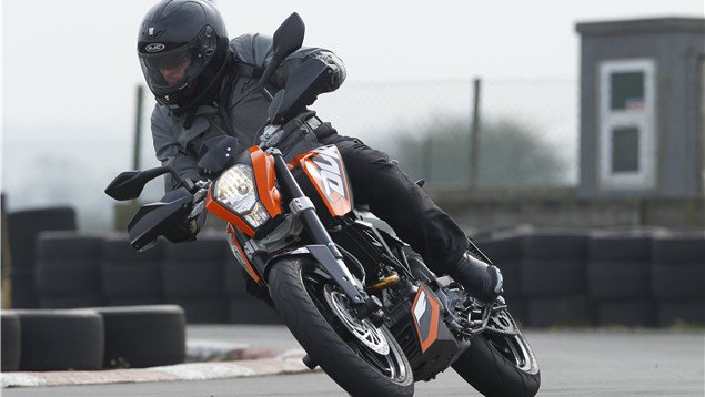 A black and orange 2011 KTM 125 Duke being ridden around a track